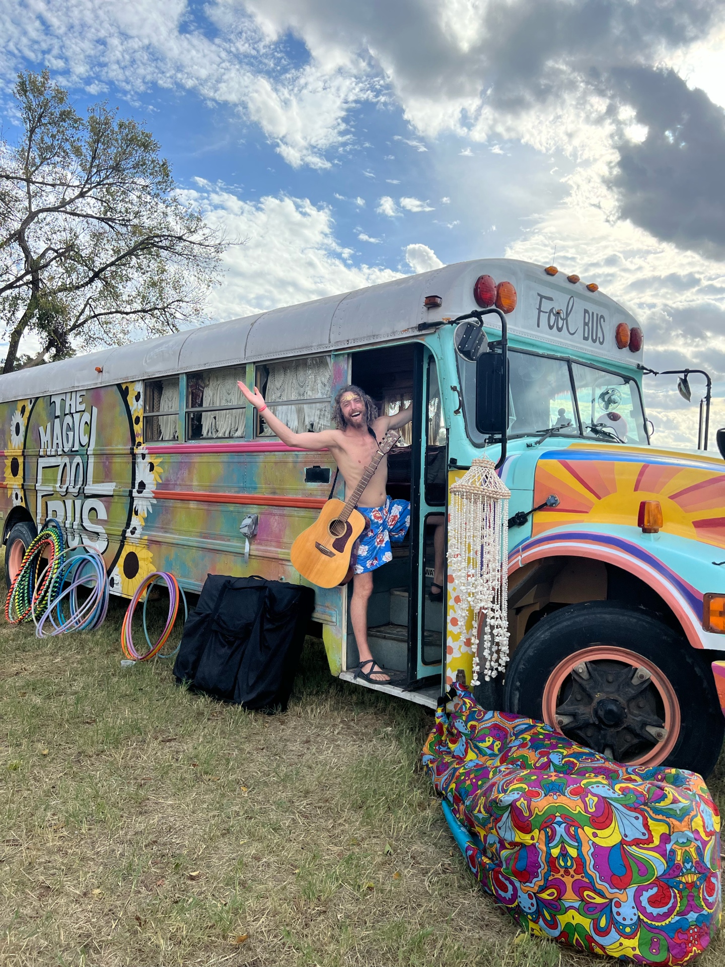 The Magic Fool Bus with guitar, hula hoops, painted details, and festival-ready energy